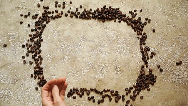 咖啡背景咖啡爱好者。从烤咖啡豆的矩形框架，里面有拷贝空间。双手将木心放在两侧。视频下载