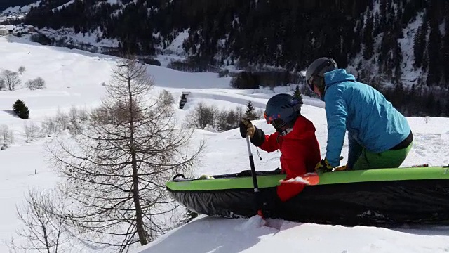 朋友们在雪坡上划着充气皮艇视频下载