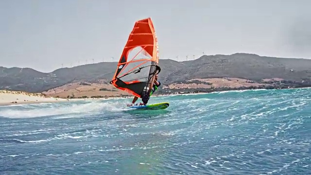 SLO MO男子做一个翻转与他的风帆冲浪在阳光视频素材