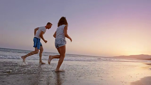 日落时分，爸爸和女儿在海滩上跑步，玩得很开心视频素材
