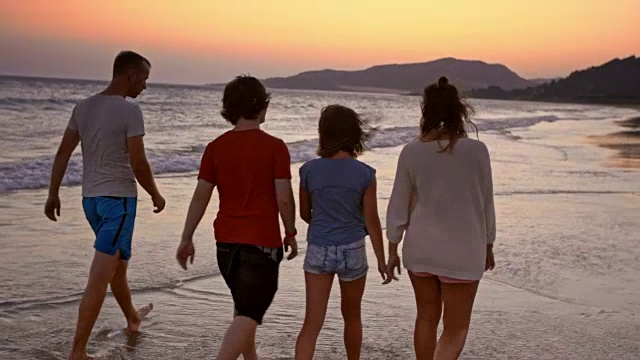 SLO MO一家四口在日落时分在海滩上散步聊天视频素材