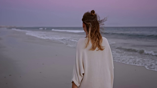 黄昏时分，一个女人在海滩上散步视频素材