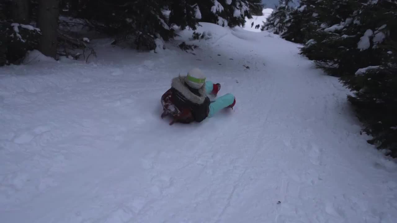 在冬天的森林里，女孩坐着雪橇下山的慢动作视频购买