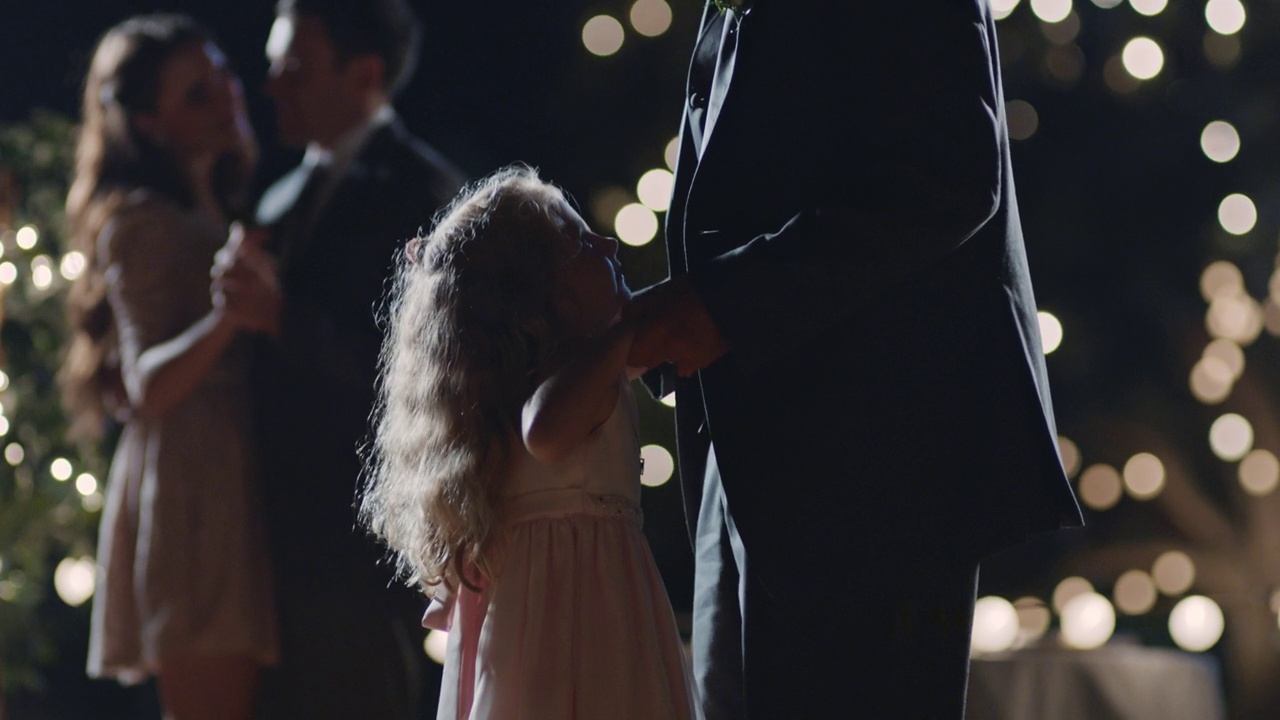 在闪烁的灯光下，小女孩在她父亲的脚上跳舞。视频素材