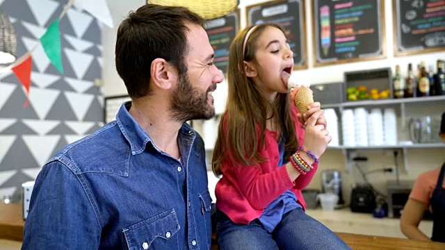 女儿和父亲在冰淇淋店享受冰淇淋，售货员递给她冰淇淋视频素材