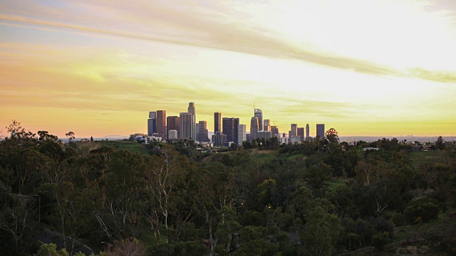 太阳落在洛杉矶的天际线上，一架飞艇飞过市中心视频素材