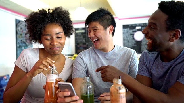 一群快乐的朋友在果汁吧看智能手机上的照片视频素材