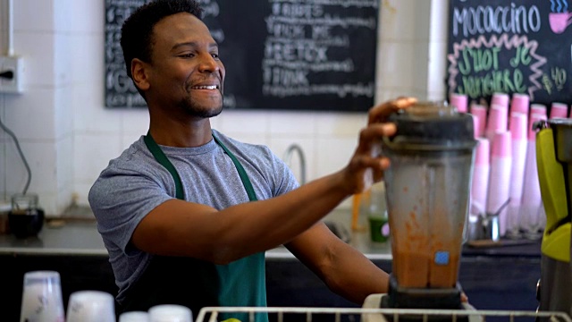 一个在果汁吧工作的黑人，把水果加到果汁机里做成果汁视频素材