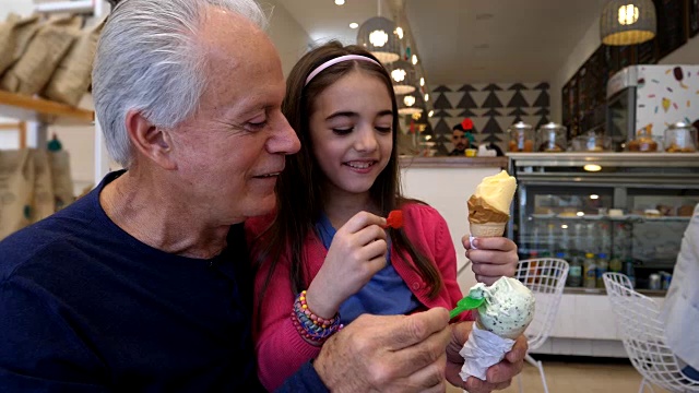 爷爷和孙女互相喂冰淇淋，看起来很开心，笑了视频素材