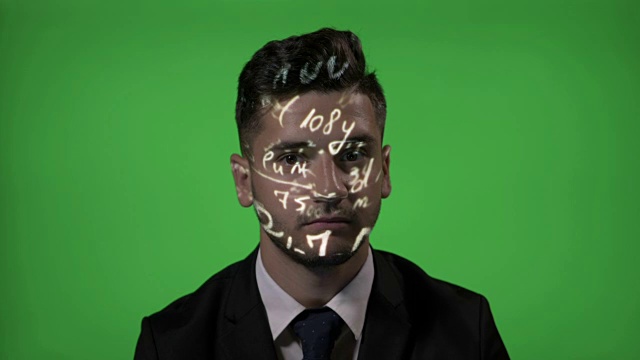 年轻的男大学教授使用增强现实的数学全息公式投影在他的脸在绿色屏幕的背景视频素材