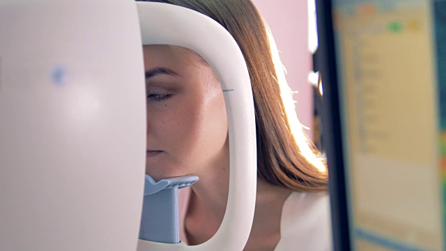 年轻女子的头部被放在光学机器上，而她的眼睛被检查的特写视频下载