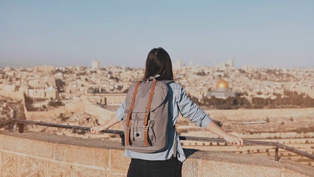 背着背包的女孩去看耶路撒冷老城。兴奋的欧洲游客高兴地举起手。以色列。4 k视频素材