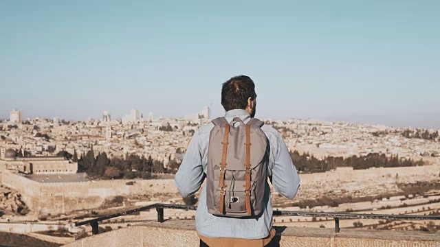 兴奋的欧洲游客环顾四周。以色列耶路撒冷。快乐微笑的男人背着背包欣赏美丽的4K风景视频素材