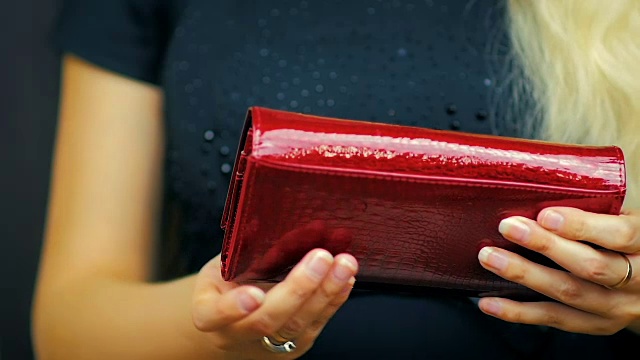 一个年轻女孩的特写关闭一个红色钱包，其中有现金和信用卡在慢动作视频素材