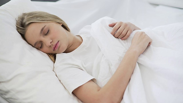 年轻漂亮的女性安静地睡在不好的，舒适的整形床垫视频下载