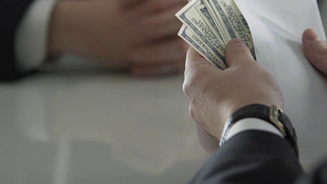 男性从商业伙伴手中接过现金，用信用卡支付视频素材