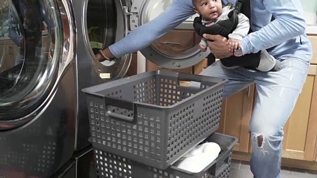 抱着婴儿的父亲在洗衣服视频素材