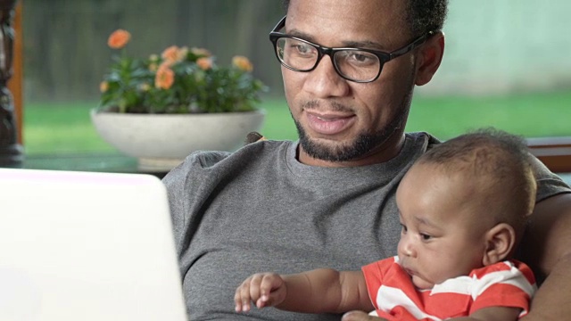 父亲和婴儿在电脑上工作视频素材