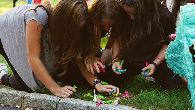 年轻女孩收集糖果从一个破碎piñata视频素材
