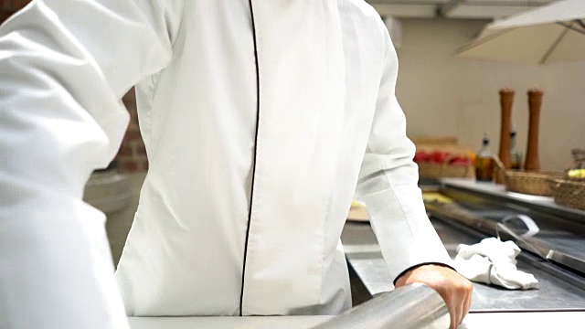 意大利餐厅的厨师用金属擀面杖微笑着做披萨视频素材