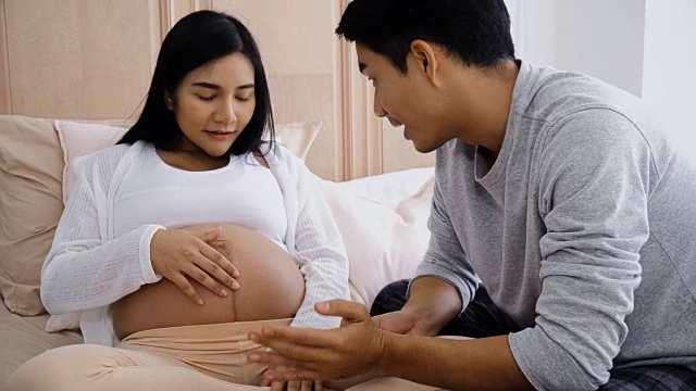 年轻的丈夫在怀孕的妻子的腹部用了护肤霜视频下载