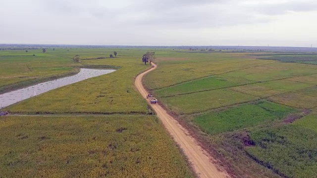 无人机拍摄:农民开着两轮拖拉机和摩托车穿过稻田视频素材