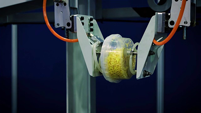 机器人的机械臂在食品生产的输送带上工作。在传送带上放置装有食物的盒子视频素材