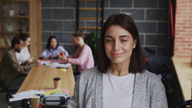年轻开朗的女企业家在忙碌的创业办公室背景下微笑着看着镜头视频素材