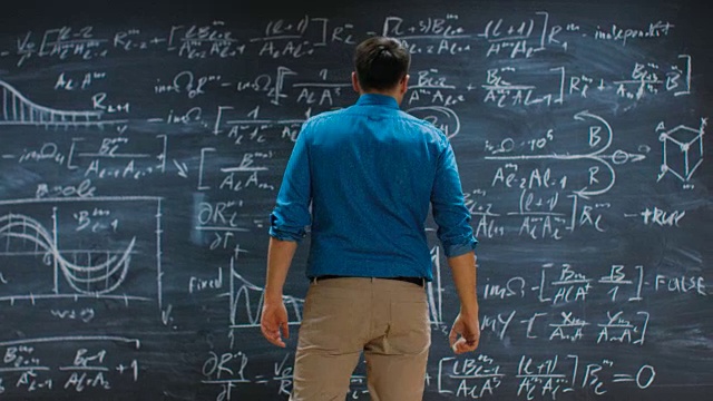 聪明的年轻数学家接近黑板并完成解决长和复杂的方程。视频素材