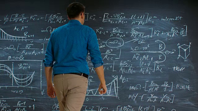聪明的年轻数学家接近大黑板和思考解决长和复杂的方程/公式。视频素材