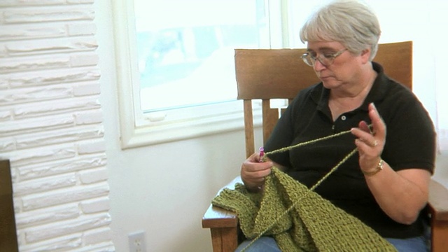 老妇人织着毛衣，对着镜头微笑视频素材