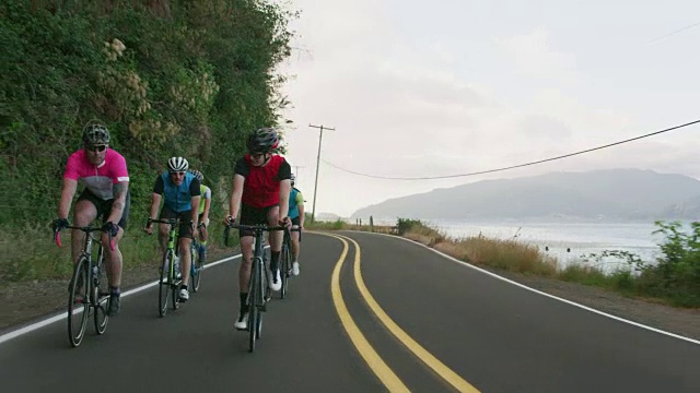 跟踪拍摄了一群骑自行车的人在乡村公路上。视频素材