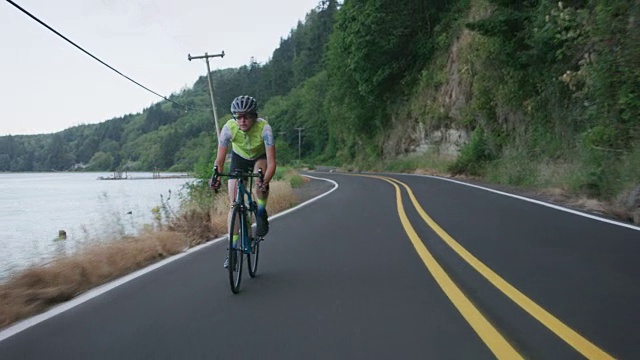 乡村公路上一个女自行车手的跟踪镜头。视频素材