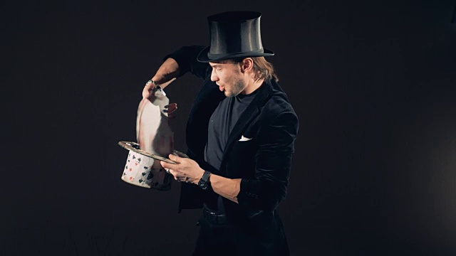 一个男巫师正在用纸牌玩把戏，把纸牌变成一顶帽子视频下载