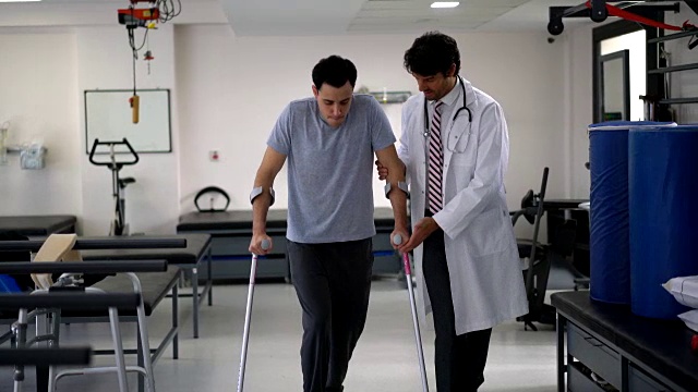 医院的骨科医生在帮助一位年轻病人第一次使用拐杖视频下载