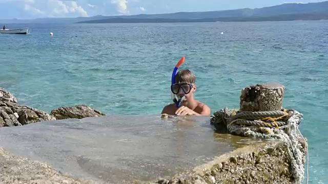 一个带着水肺潜水设备的男孩把贝壳从海底拉出来视频下载