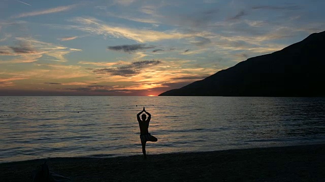 日落时分，一个成年人在海滩上做瑜伽视频下载