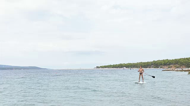 一个成年人和冲浪板在海滩附近漂浮视频下载