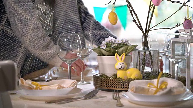 年轻女子用兔子和鸡蛋装饰复活节餐桌视频素材