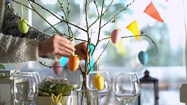 年轻女子用兔子和鸡蛋装饰复活节餐桌视频素材