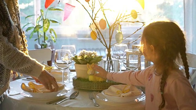 一位妇女和她的小女儿正在用兔子和鸡蛋装饰复活节的餐桌视频素材