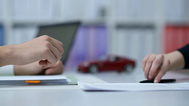 汽车经销商或保险公司向客户展示合同，模型车在后台视频素材