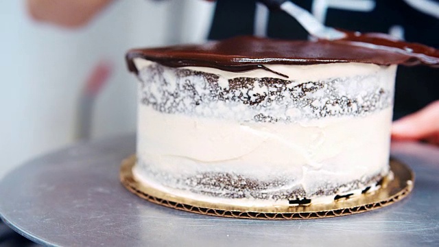 面包师傅用刀在蛋糕上涂抹融化的巧克力的特写视频素材