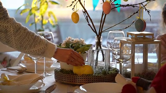 一位妇女和她的小女儿正在用兔子和鸡蛋装饰复活节的餐桌视频下载