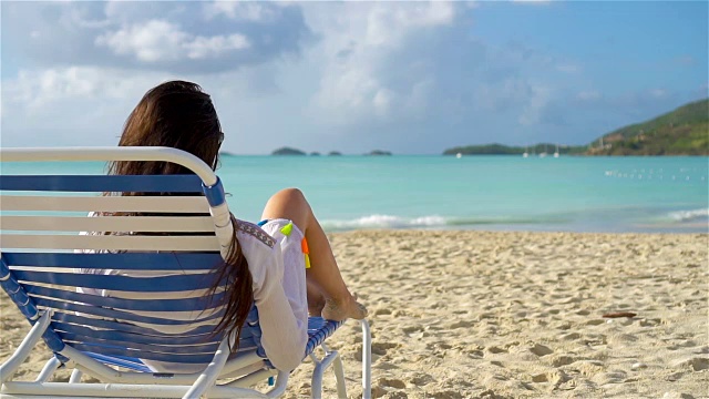 放松和享受暑假，女人躺在沙滩上的日光浴床上。慢动作视频购买