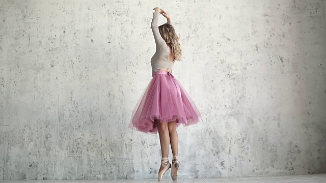 踮脚的芭蕾舞女演员正踮着脚尖旋转。芭蕾舞演员在一个古典包在一个轻墙的背景视频素材