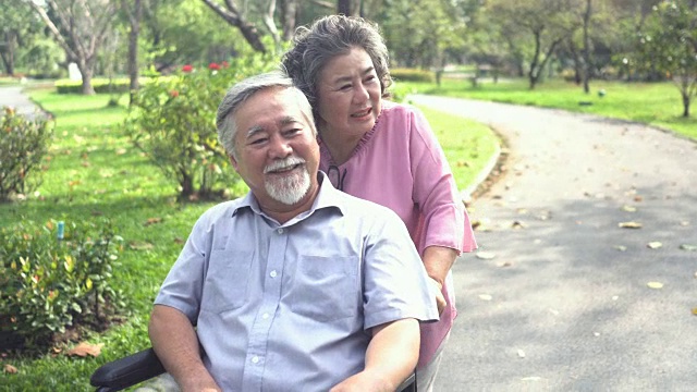 以下正面视图:年长的妻子带着亚洲丈夫在轮椅上休息，但他不能和她一起走视频下载