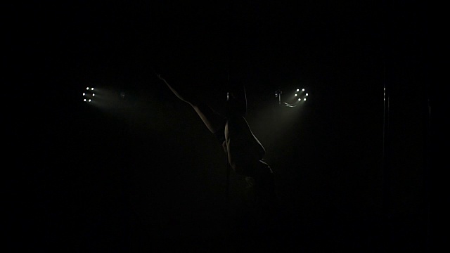 迷人的女孩在黑暗中靠近一根钢管跳舞。视频下载