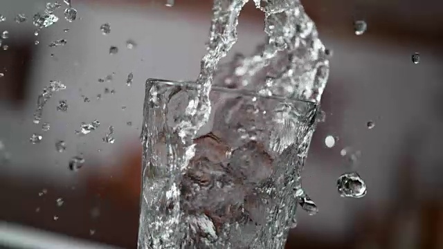 将冷的纯净水倒入玻璃杯中。超级慢动作视频素材