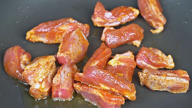 把肉片放在煎锅里煎。烤猪肉里脊在热煎锅上生的肉块在煎锅上。视频下载